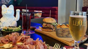 A dining table with a variety of food items, a glass of beer, and a decorative ceramic figure.