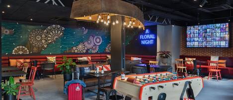 A cozy lounge area with a foosball table, comfortable seating, and a large mural.