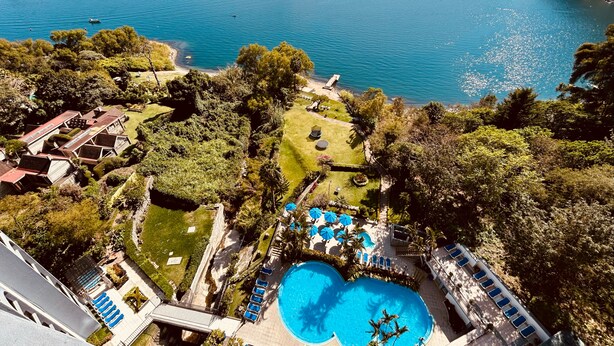 Et resort med swimmingpool, liggestole og udsigt over en sø og bjerge.