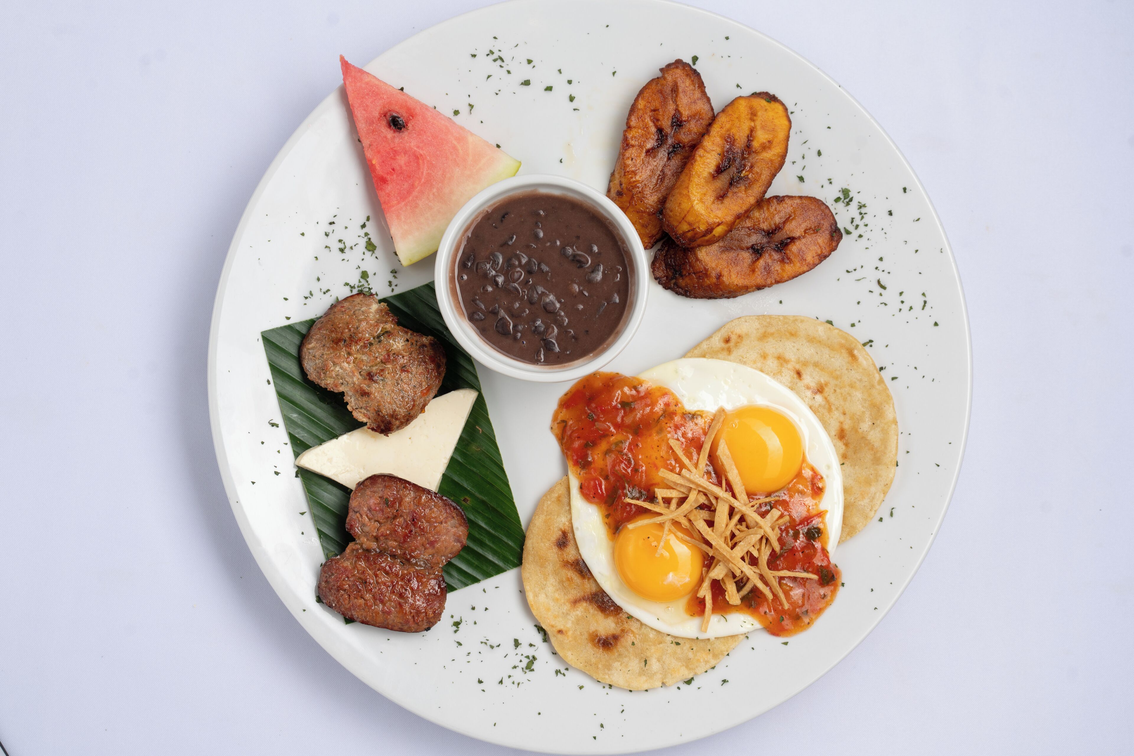 Un plato con diversos alimentos, incluyendo huevos, carne y plátanos.