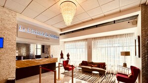 Et hotellets reception område med en marmor disk, en lysekrone, en receptionsskranke, en sofa og en rød lænestol.
