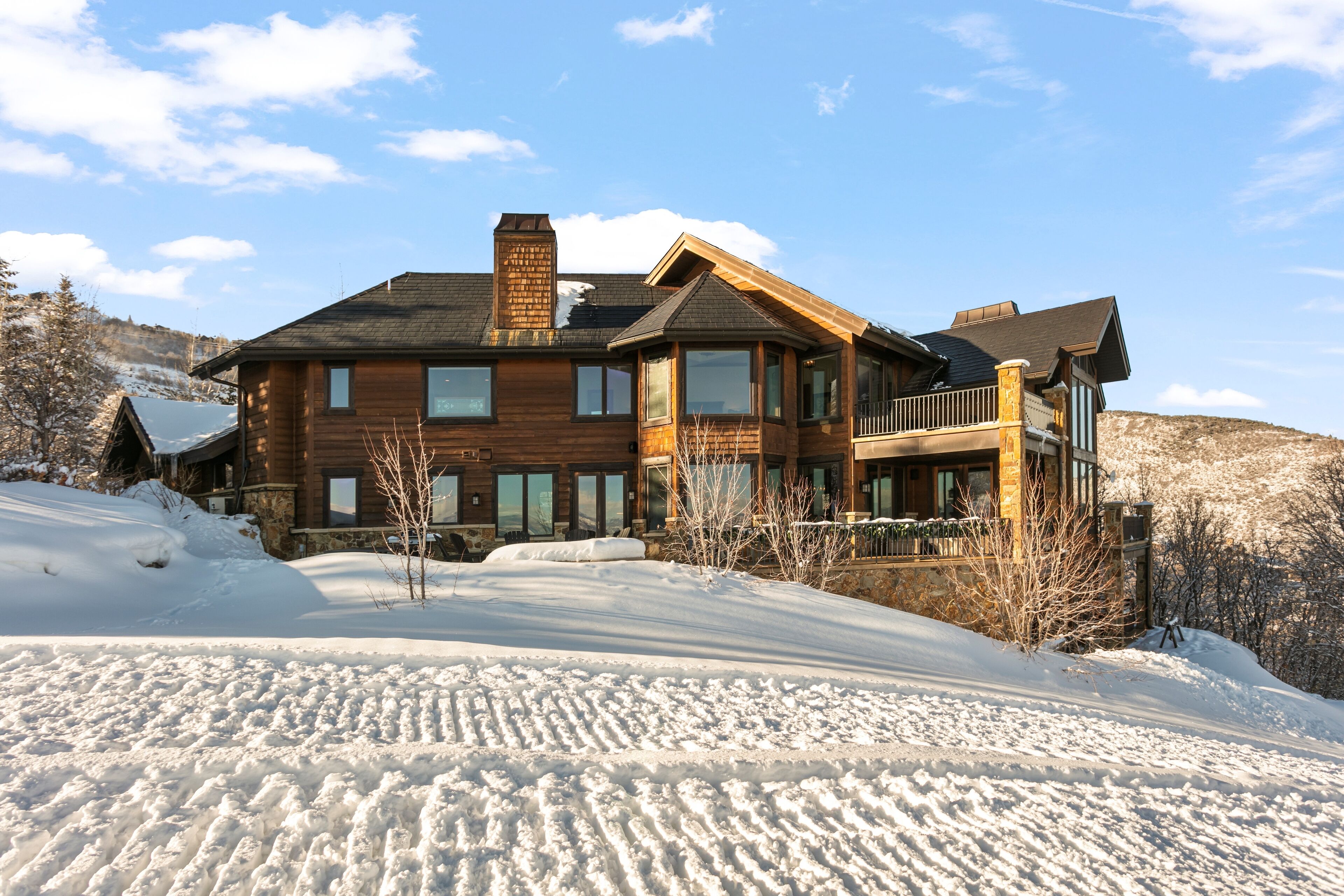 A large wooden house with multiple windows and a balcony, surrounded by snow.