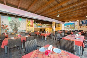 An outdoor dining area with wicker furniture and red tablecloths.