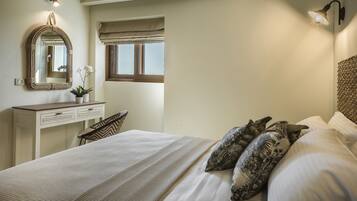 A bedroom with a bed, a bedside table, a mirror, a window with blinds, and a wall-mounted lamp.