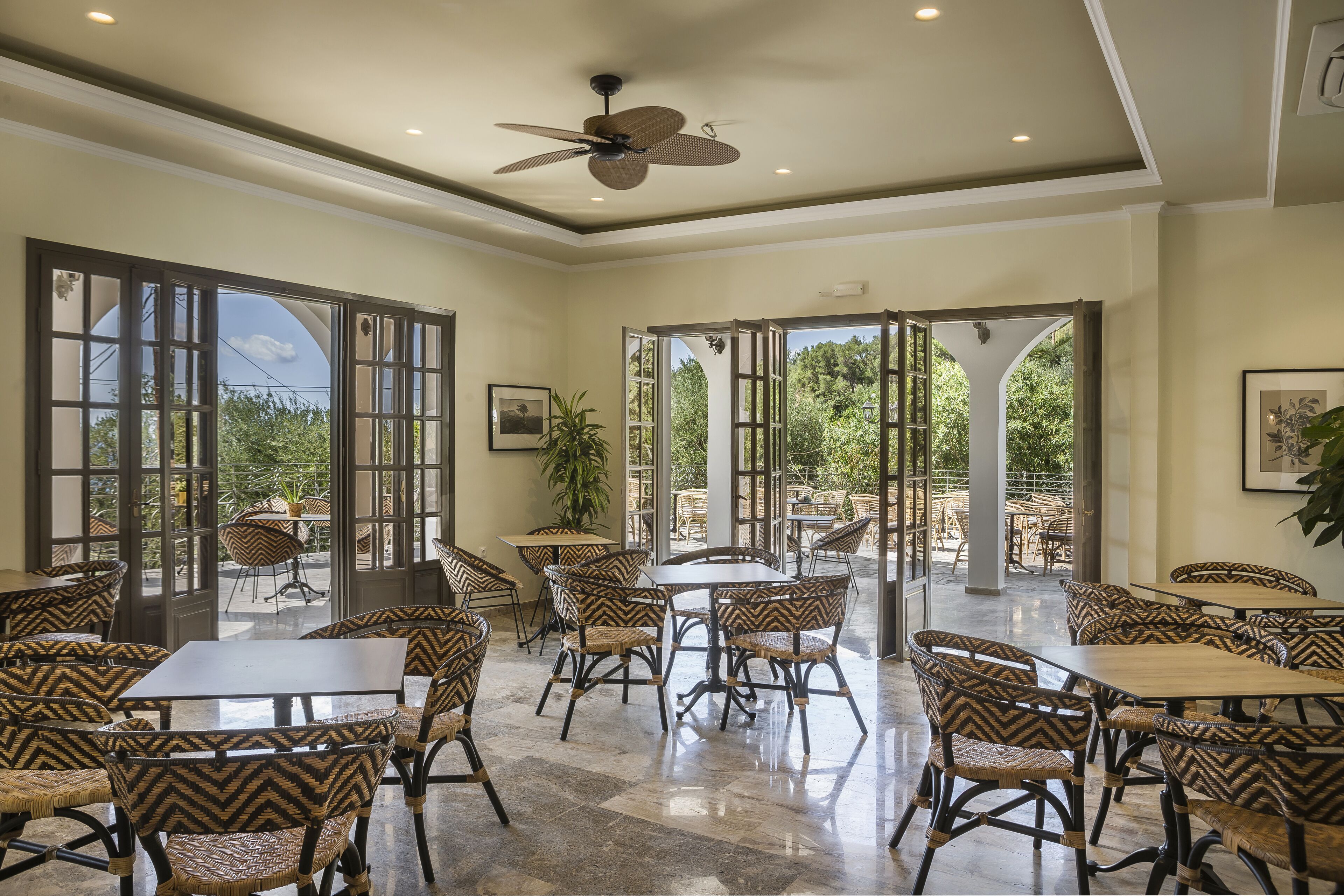 A spacious indoor dining area with high ceilings, large windows, and a ceiling fan.