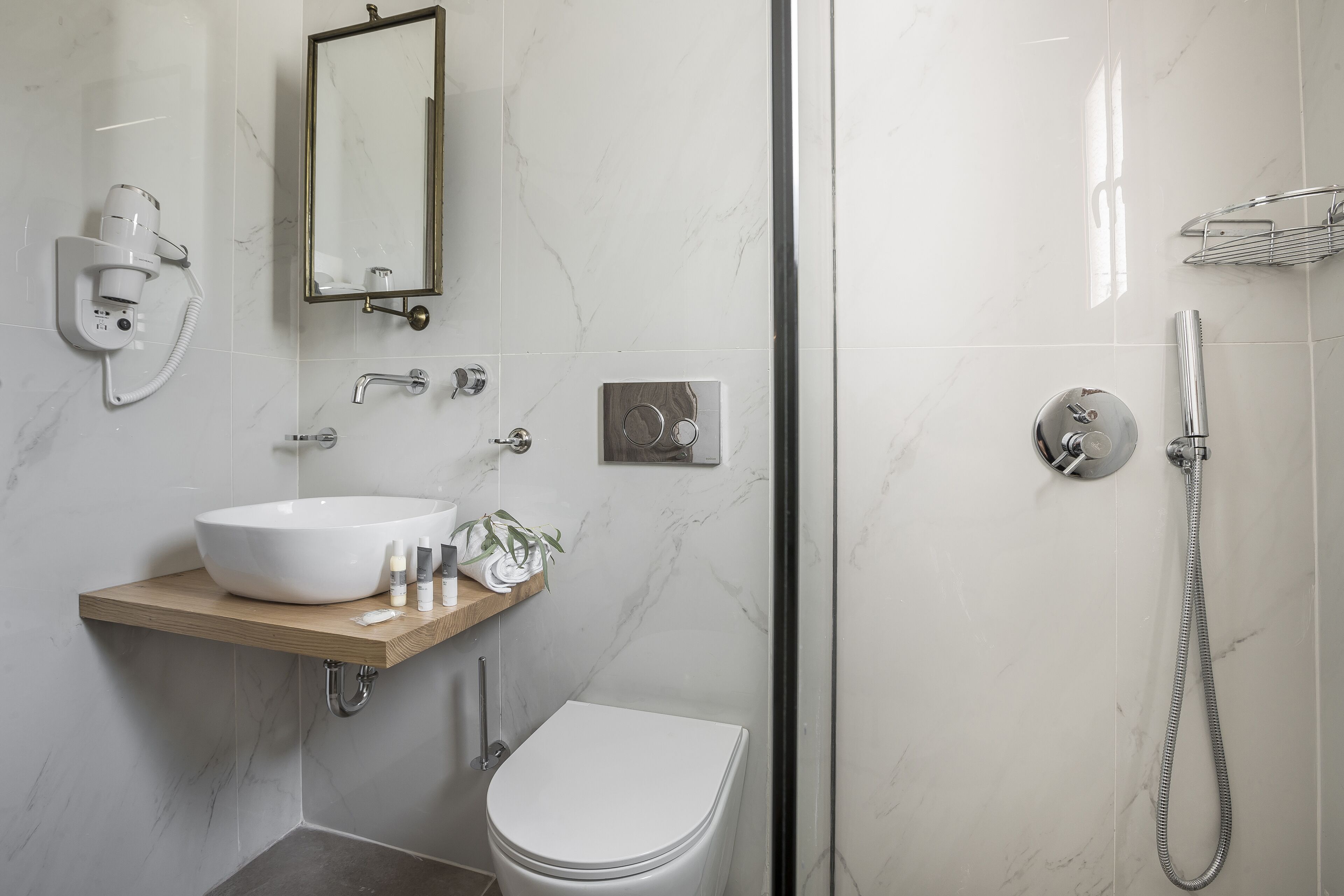 Un baño moderno con lavamanos, inodoro y ducha blancos.