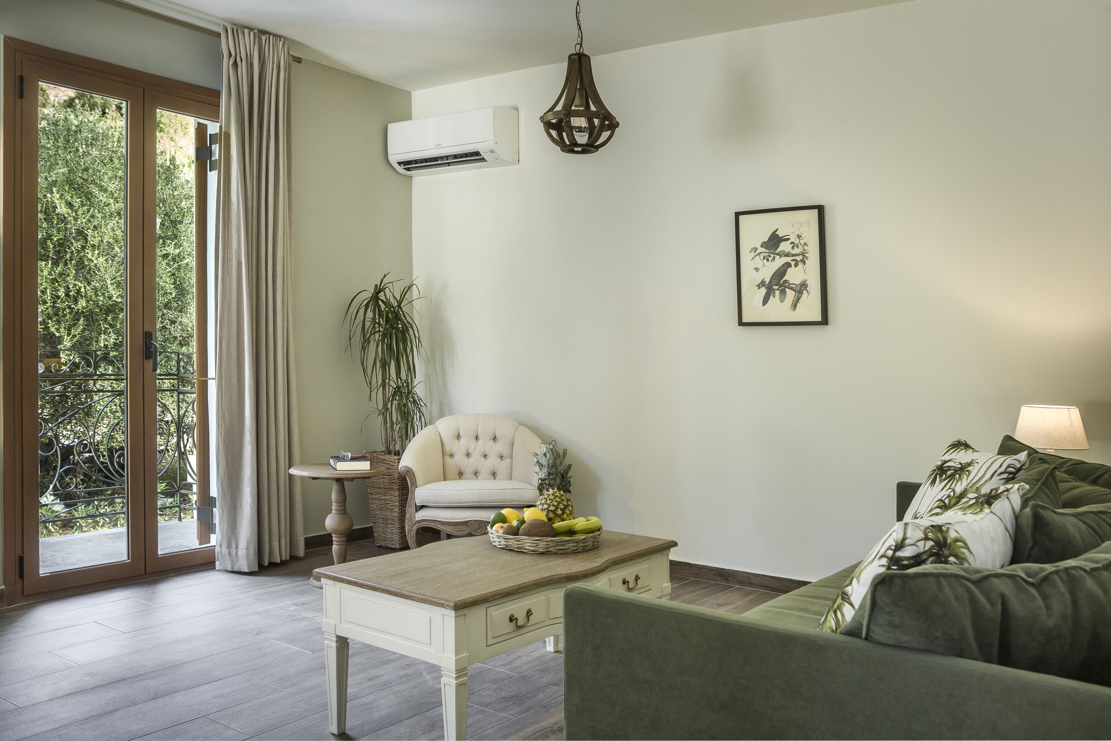A living room with a sofa, a table with a fruit basket, a chair, a lamp, and a picture on the wall.