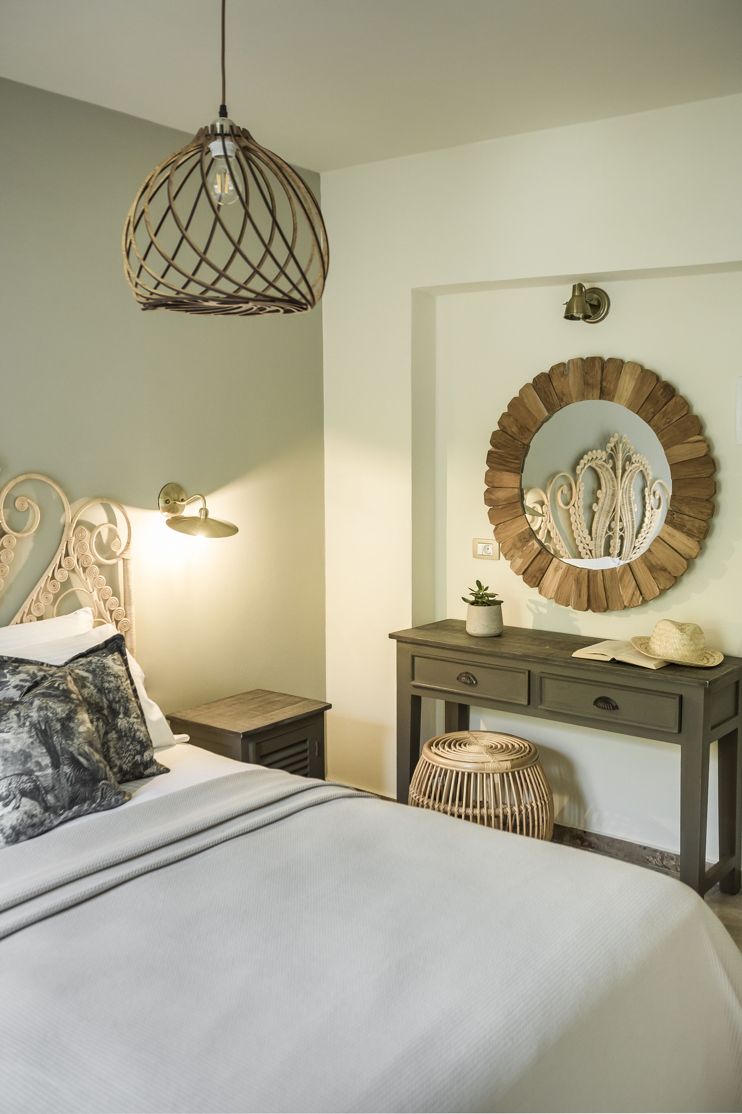 Un dormitorio con cama, lámpara de noche, cómoda, espejo y lámpara colgante.