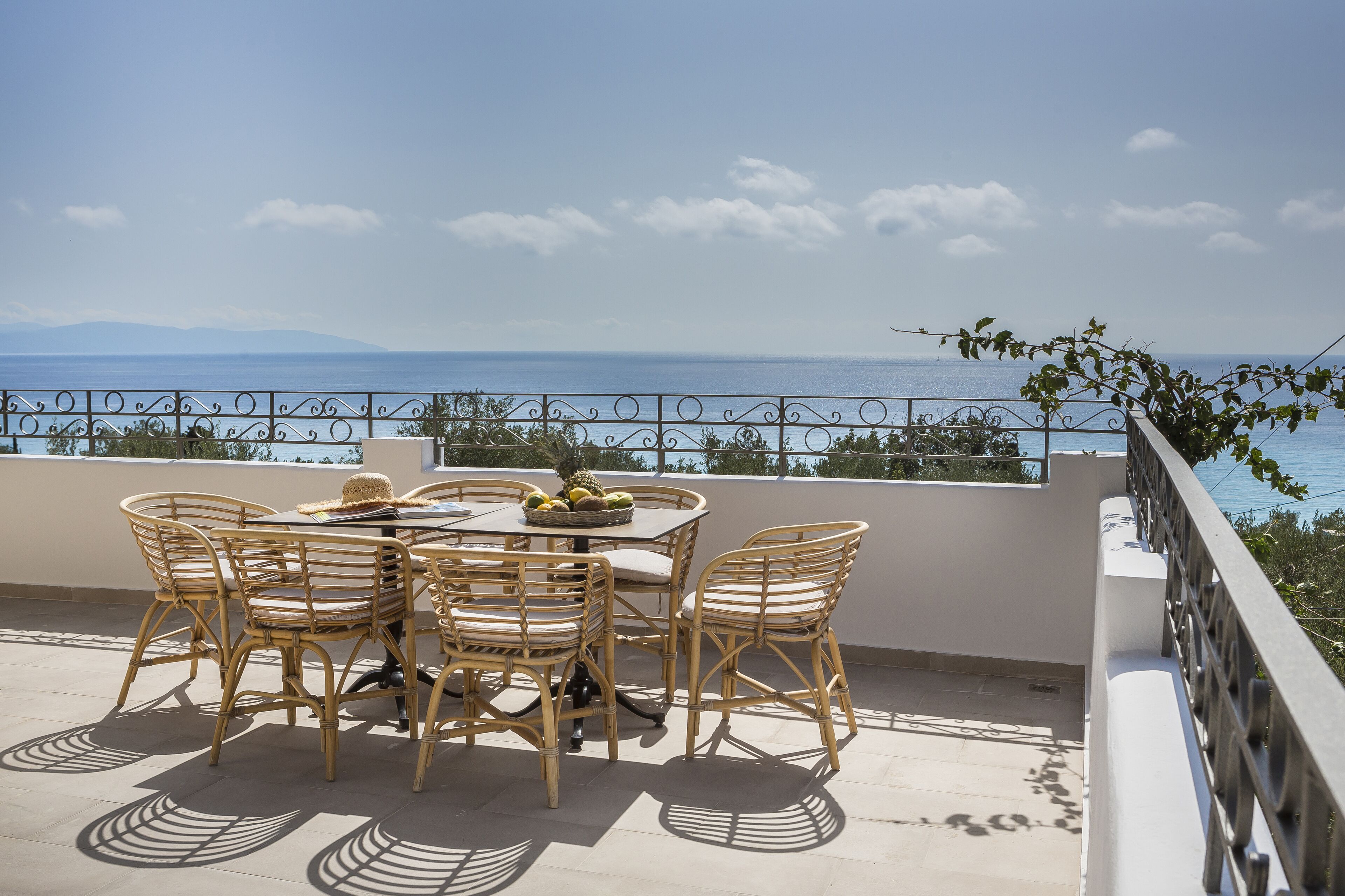 A terrace with a table and chairs, overlooking a coastal view.