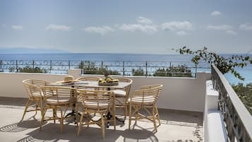 A terrace with a table and chairs, overlooking a coastal view.