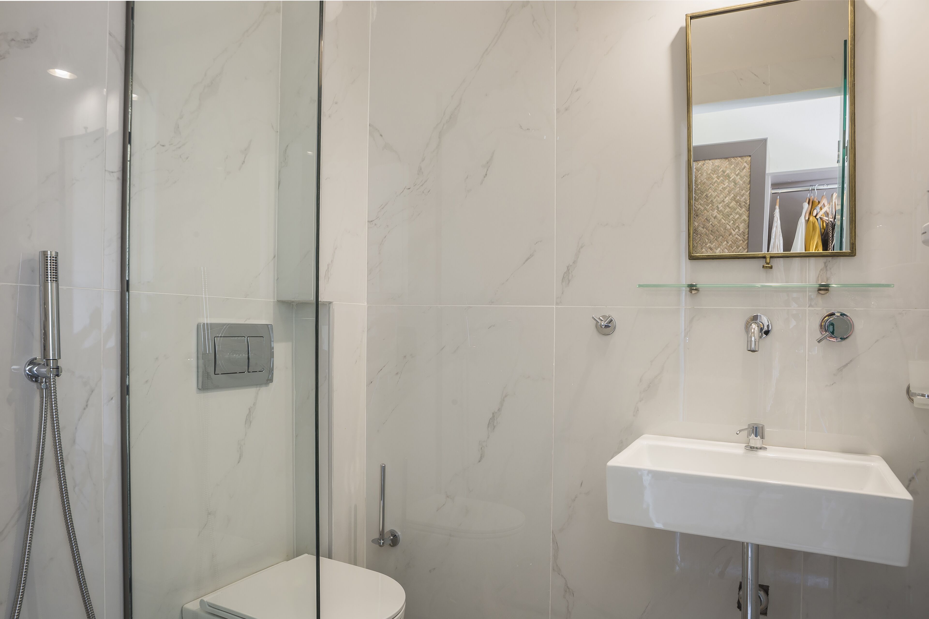 A modern bathroom with a glass shower enclosure, a white sink, and a mirror above the sink.