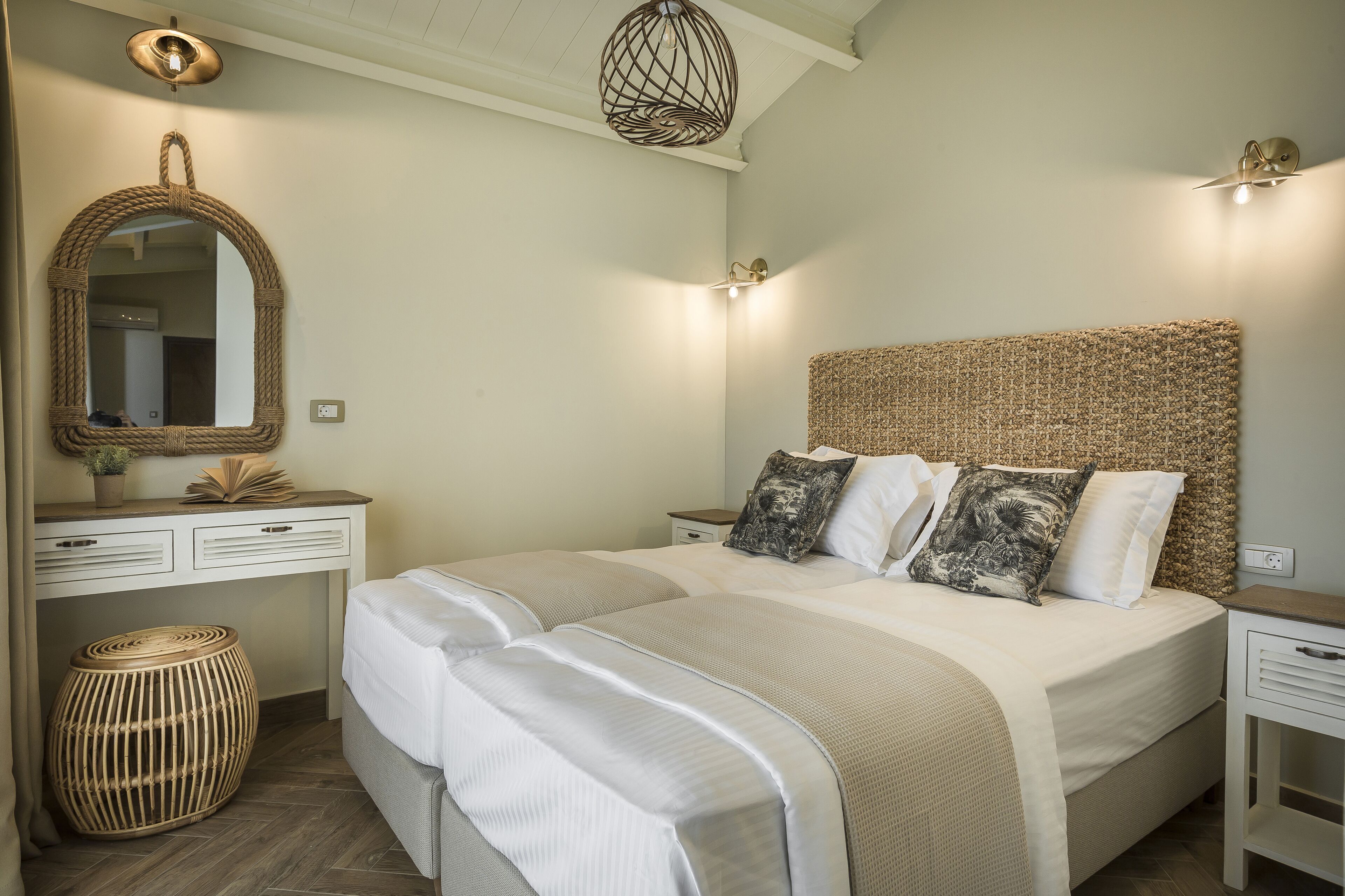 Une chambre à coucher avec un grand lit, une table de chevet, un miroir et un luminaire suspendu.