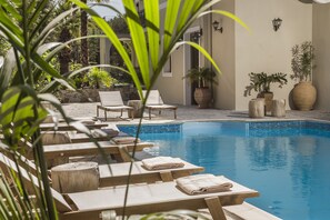 A poolside area with lounge chairs, a tiled pool, and potted plants. - La Signora Hotel (Kefalonia)