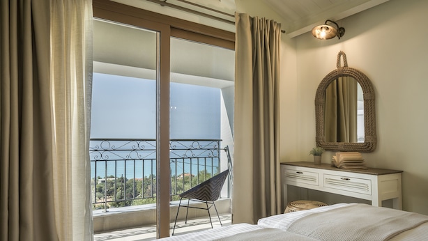 Un dormitorio con cama, cómoda, silla y vistas al exterior.