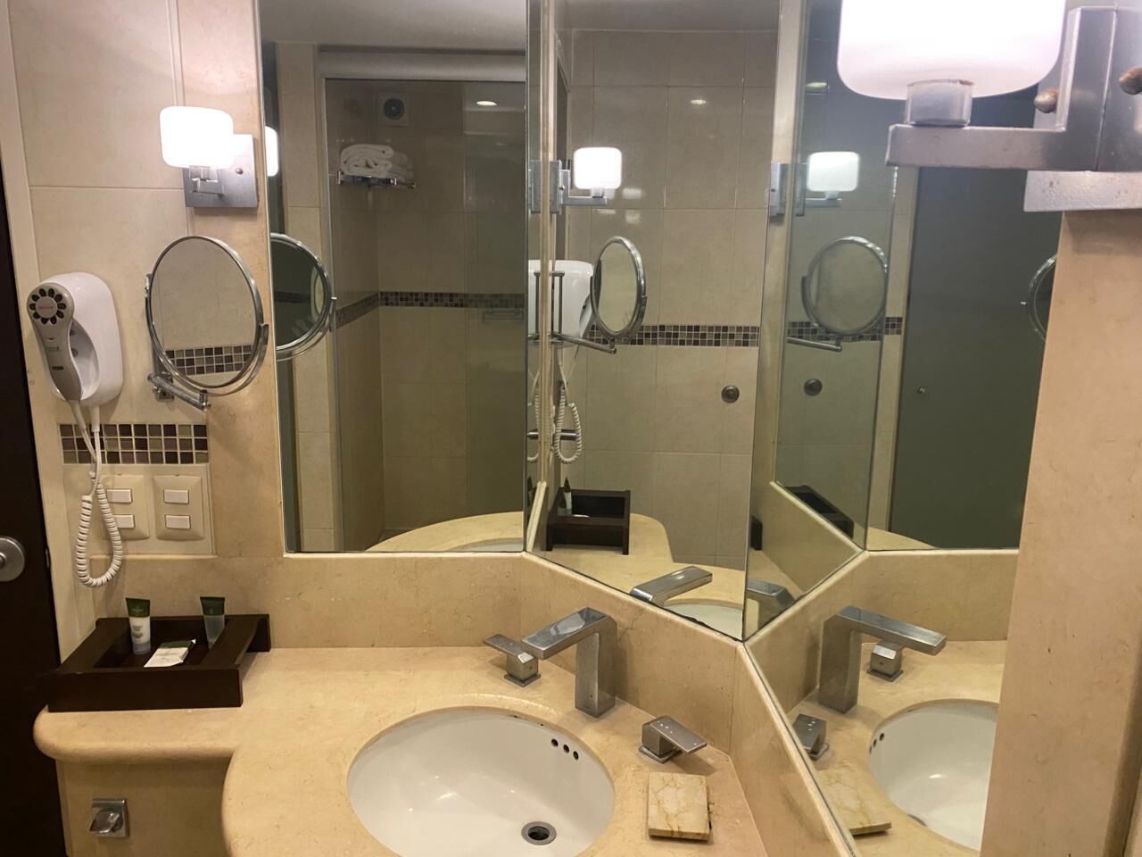 Une salle de bain d’hôtel équipée de deux lavabos, d’un sèche-cheveux, d’un miroir et d’un distributeur de serviettes.