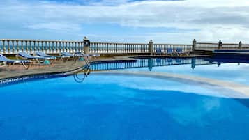 Una piscina al aire libre, sombrillas, tumbonas