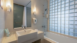 A modern bathroom with a large sink, a mirror, a glass shower enclosure, and a view through a window with a grid pattern. - Holiday Inn Express Tianjin Heping by IHG (Tianjin)