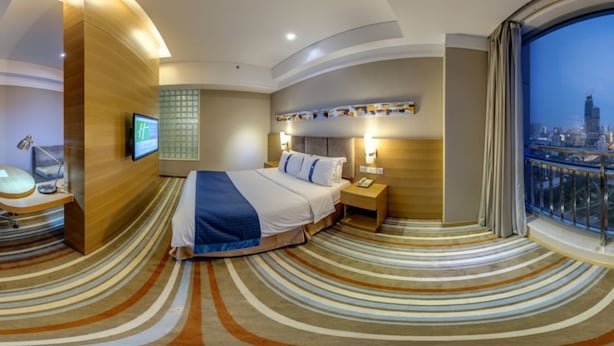 A modern hotel room with a curved ceiling, a large bed, a TV, a desk, and a city view. - Holiday Inn Express Tianjin Heping by IHG (Tianjin)