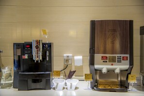 A coffee station with two coffee machines, a hot water dispenser, and sugar and coffee dispensers.
