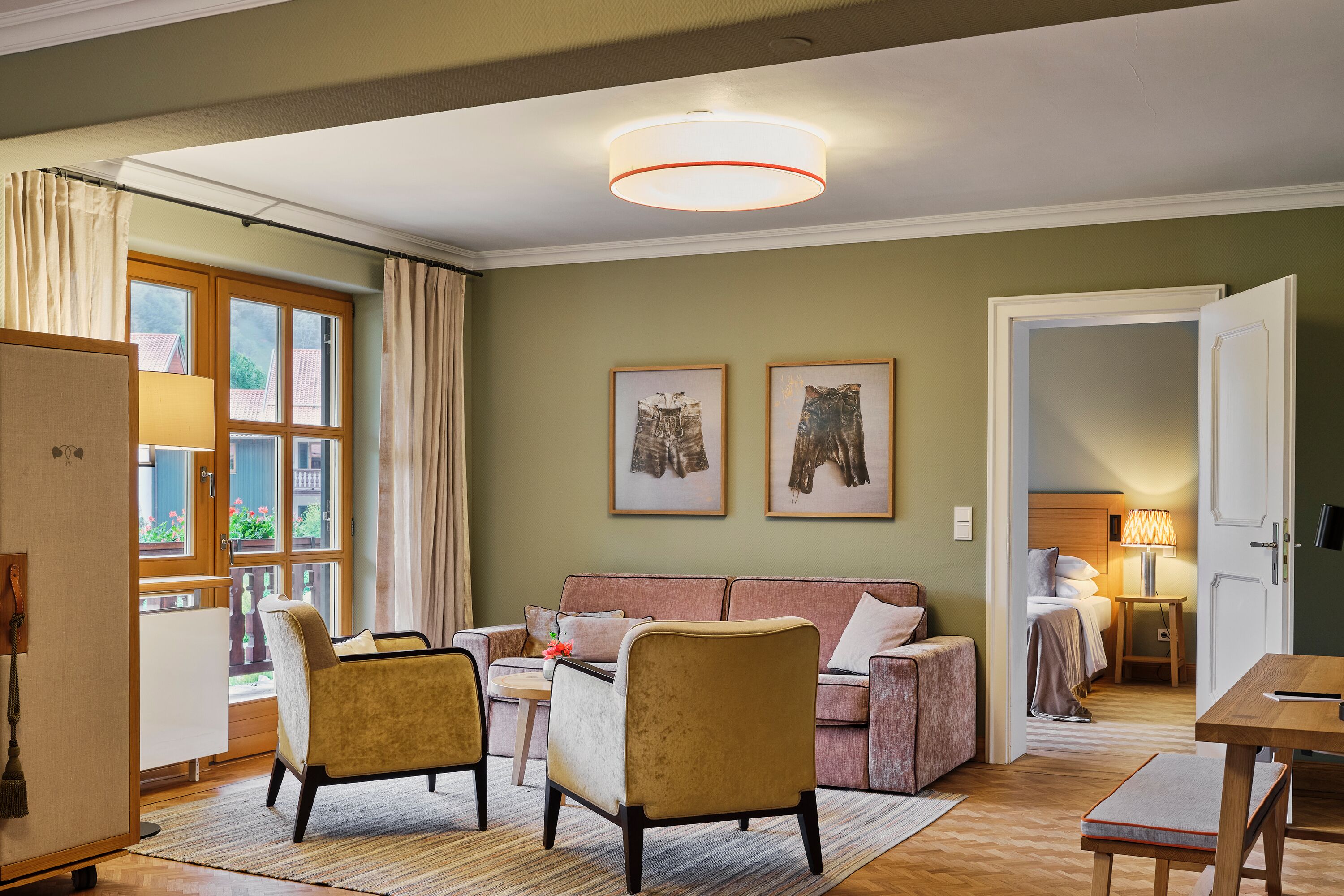 Ein helles Wohnzimmer mit einer Couch, Sesseln, einem Esstisch und Blick auf einen Balkon.