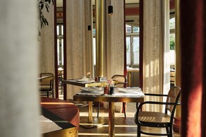 A dining area with a wooden table, chairs, and a vase with flowers. - Spa & Resort Bachmair Weissach, LUXURY FAMILY RESORT (Kreuth)