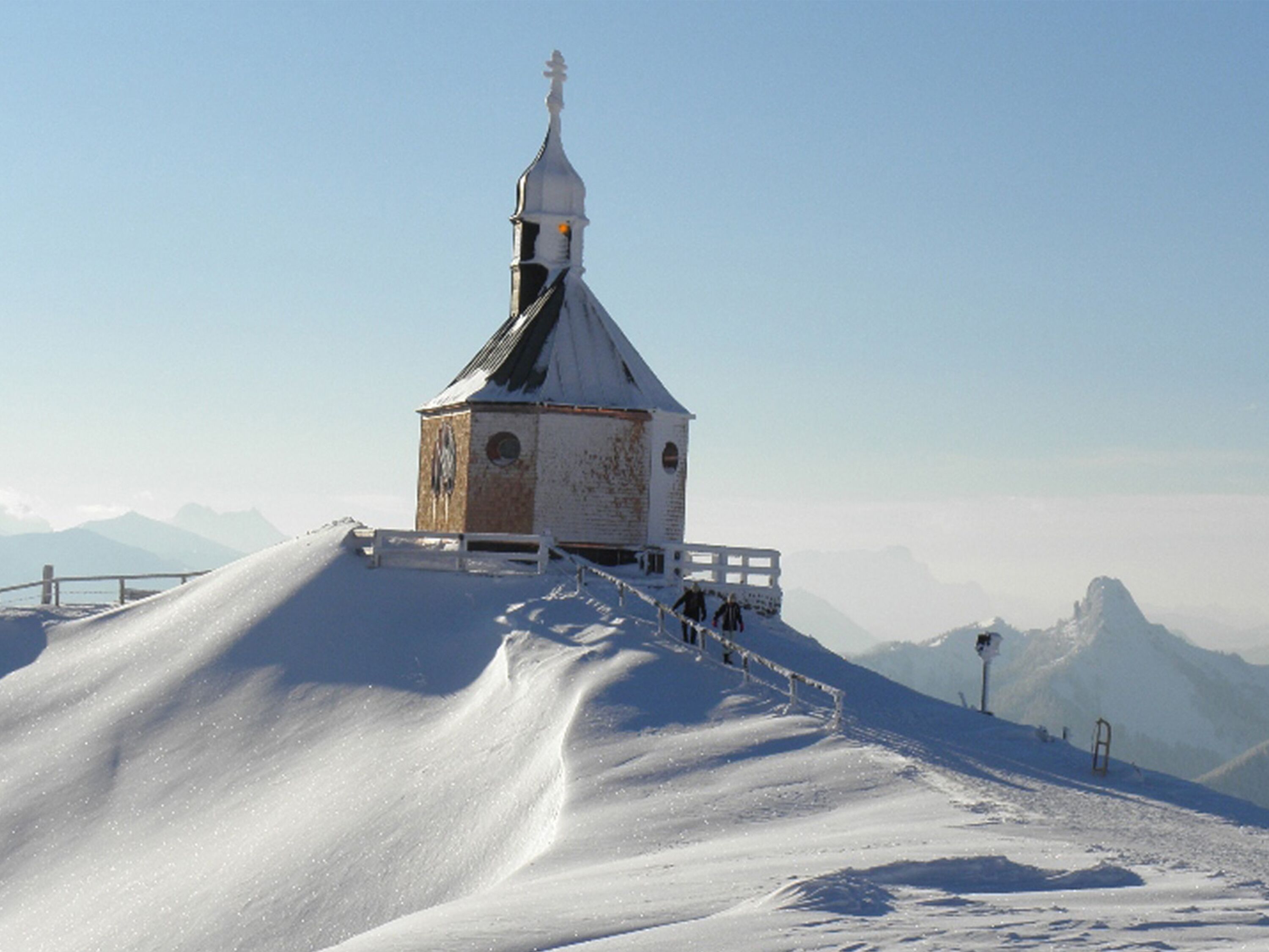 A snow-covered church with a bell tower on a hill.