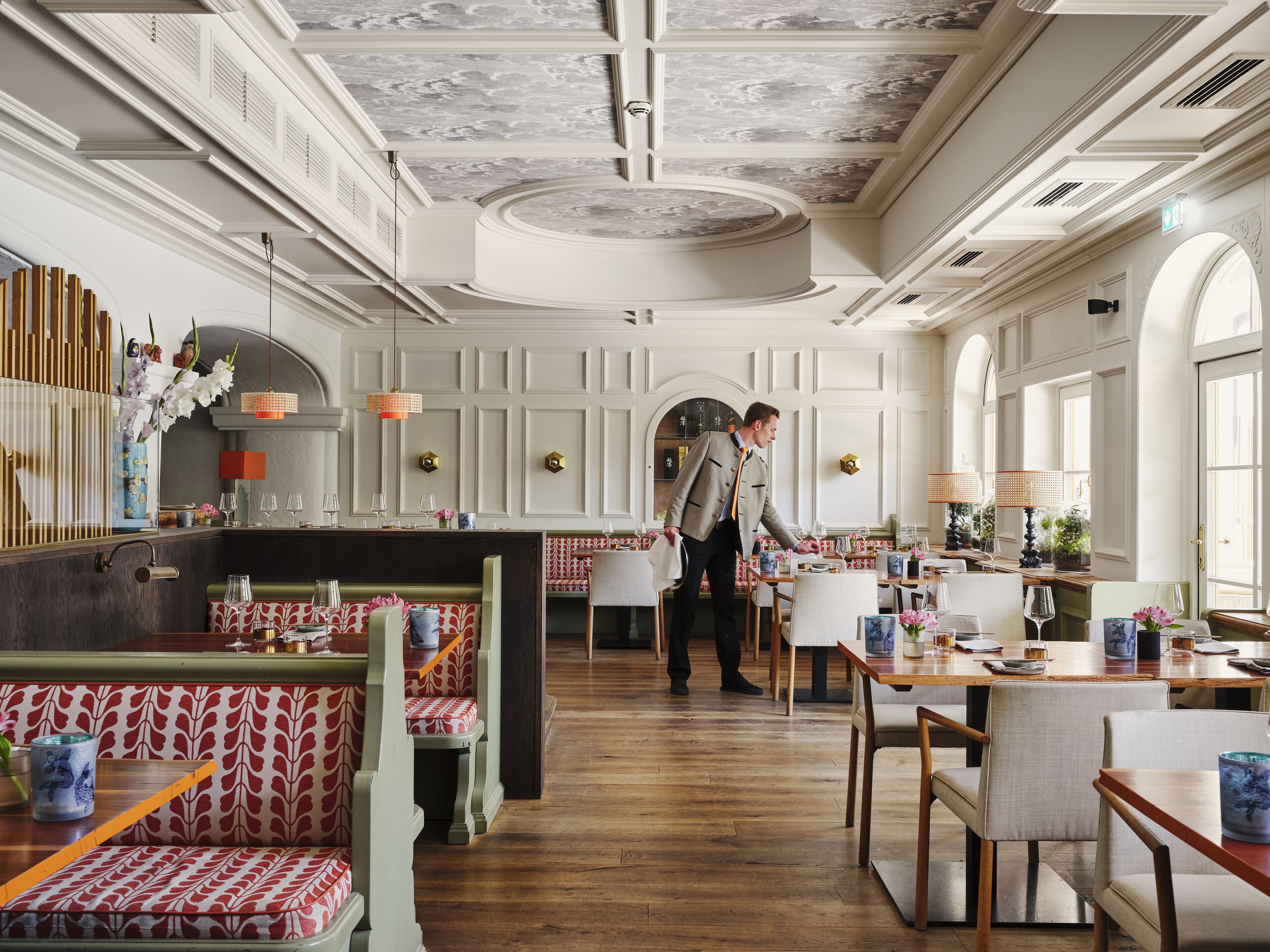 A spacious restaurant with high ceilings, ornate moldings, and a central bar area.