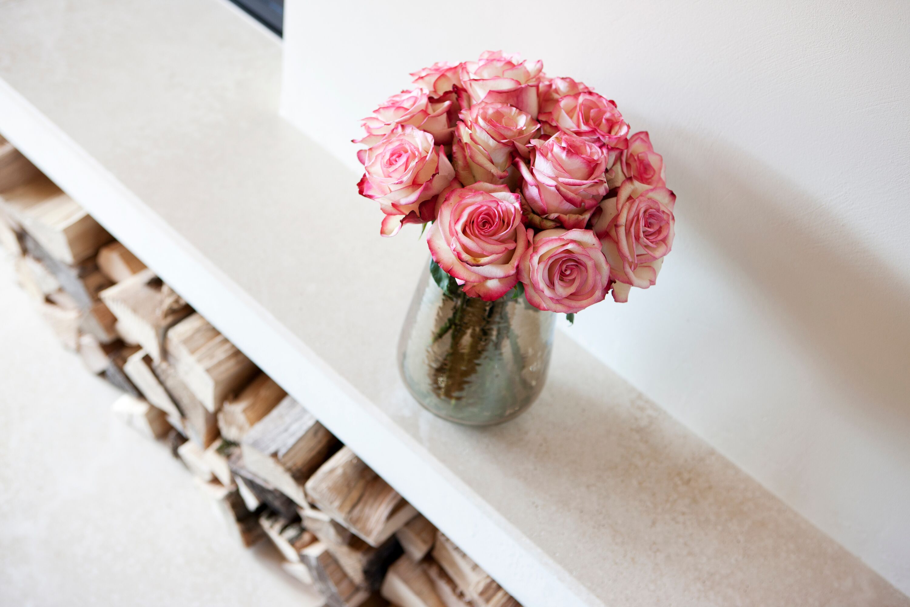 Eine Vase mit rosa Rosen auf einer weißen Oberfläche.