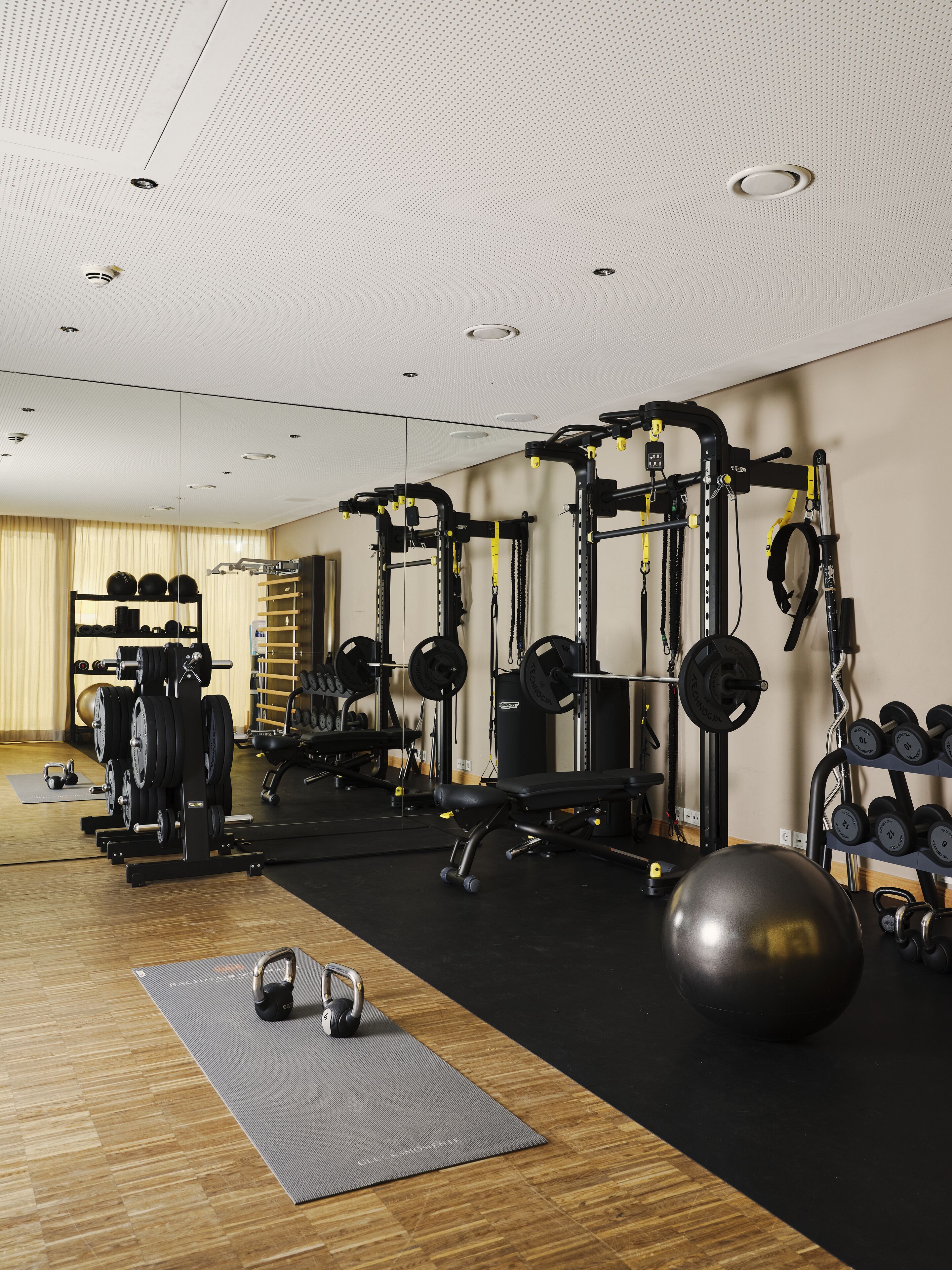 Una palestra con diverse attrezzature per l'allenamento, tra cui macchine per pesi, pesi liberi e palle da ginnastica.