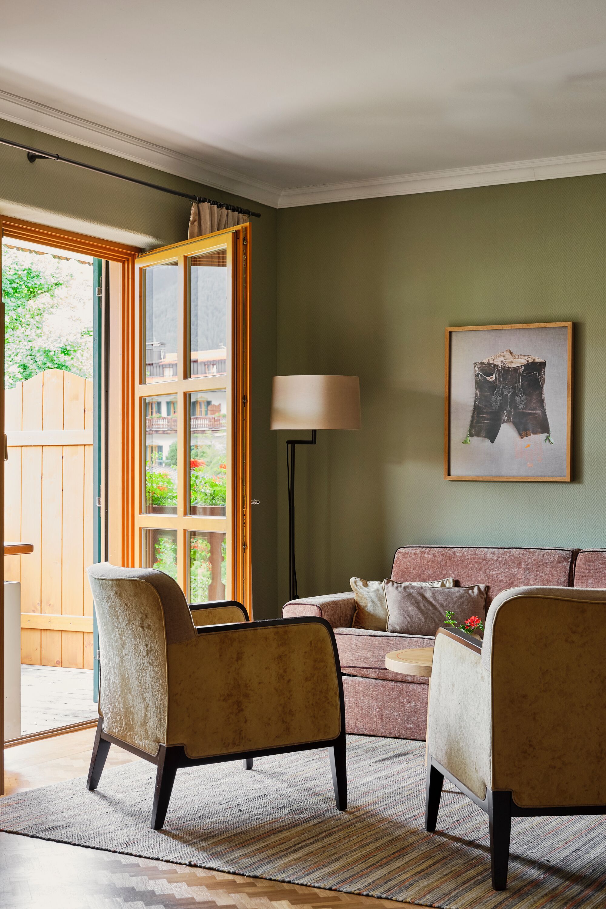A living room with a sofa, two armchairs, a lamp, and a framed artwork.