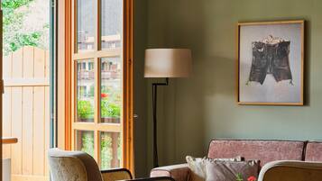 A living room with a sofa, two armchairs, a lamp, and a framed artwork.