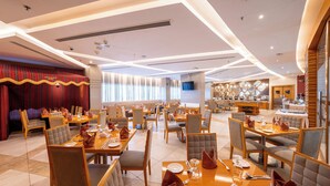 Un restaurante amplio con varias zonas de comedor, iluminación moderna y diversas opciones de asientos.