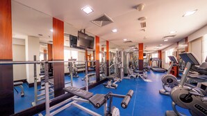 Un gimnasio con equipos de ejercicio variados, espejos y suelo azul.