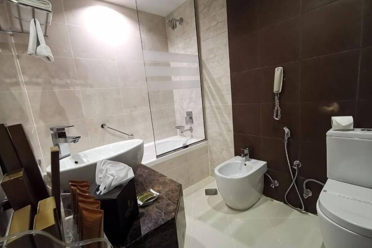 A modern bathroom with a bathtub, bidet, toilet, and a vanity with a mirror.