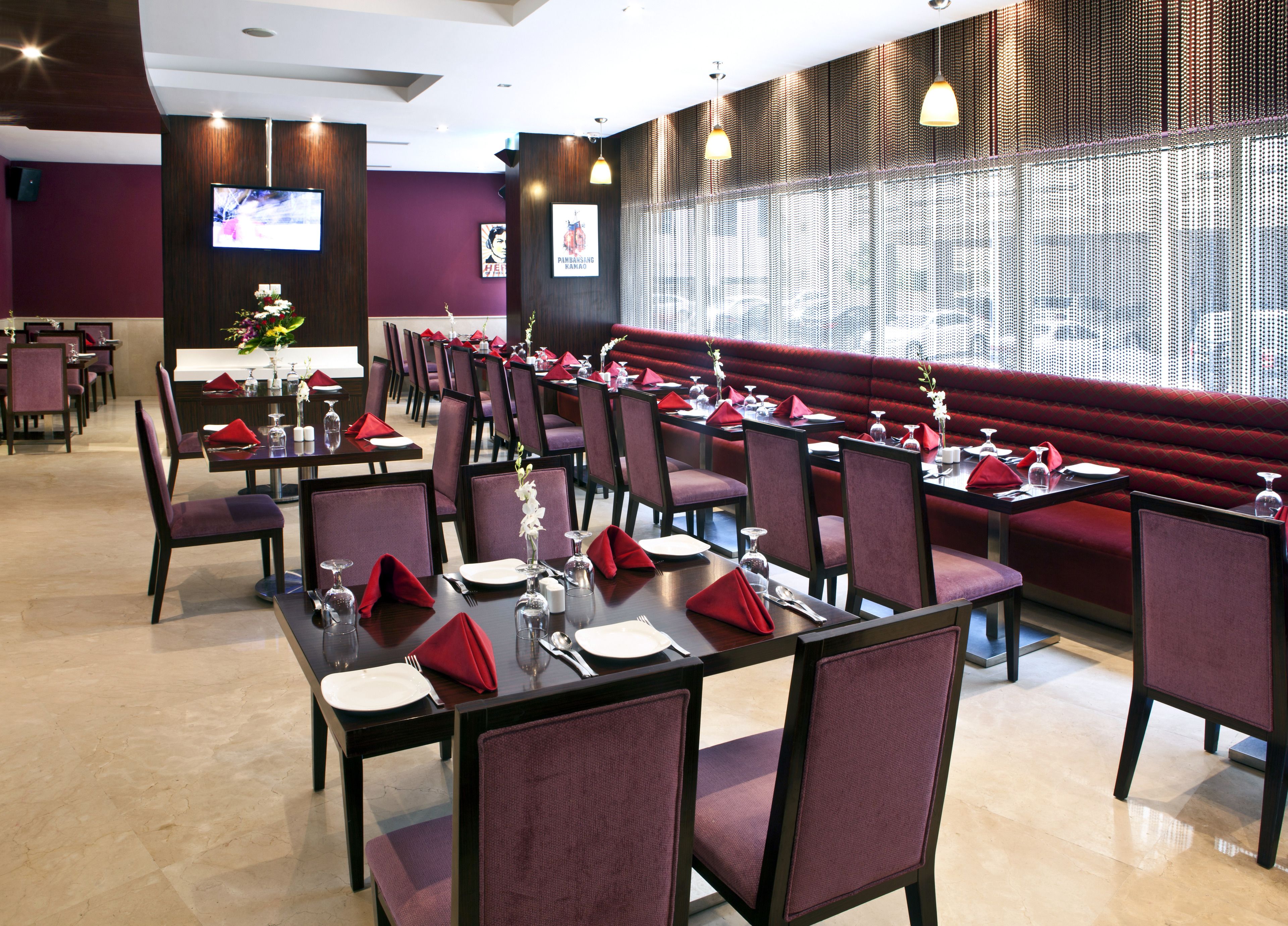 Un restaurante con varias mesas y cabinas, cada una con servilletas rojas, platos blancos y cubiertos.