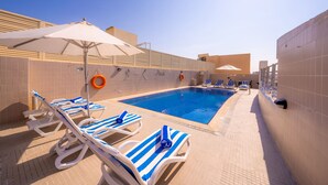 Una piscina con sillones de descanso y sombrillas.