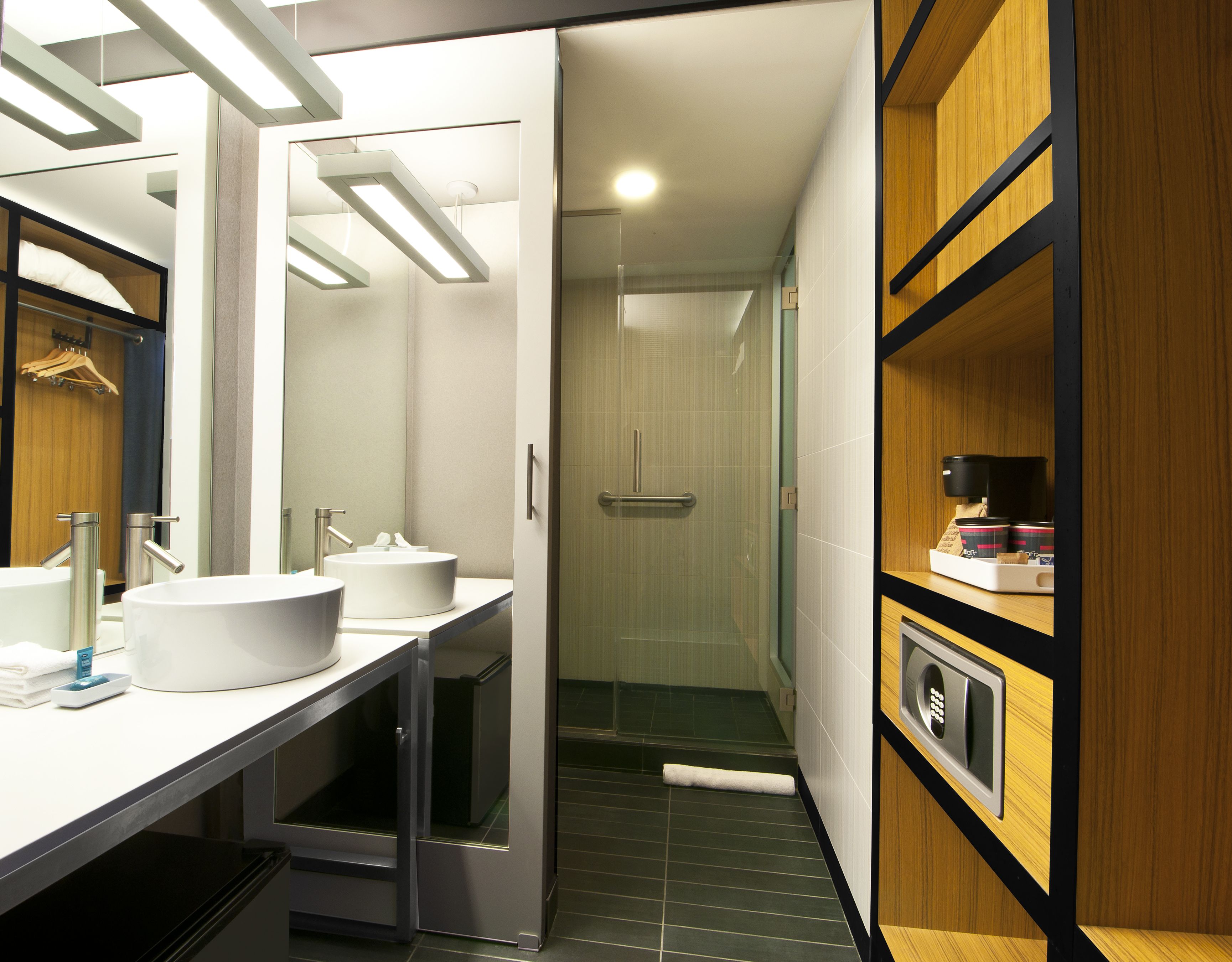 Une salle de bain moderne avec deux lavabos, un miroir et un espace douche.