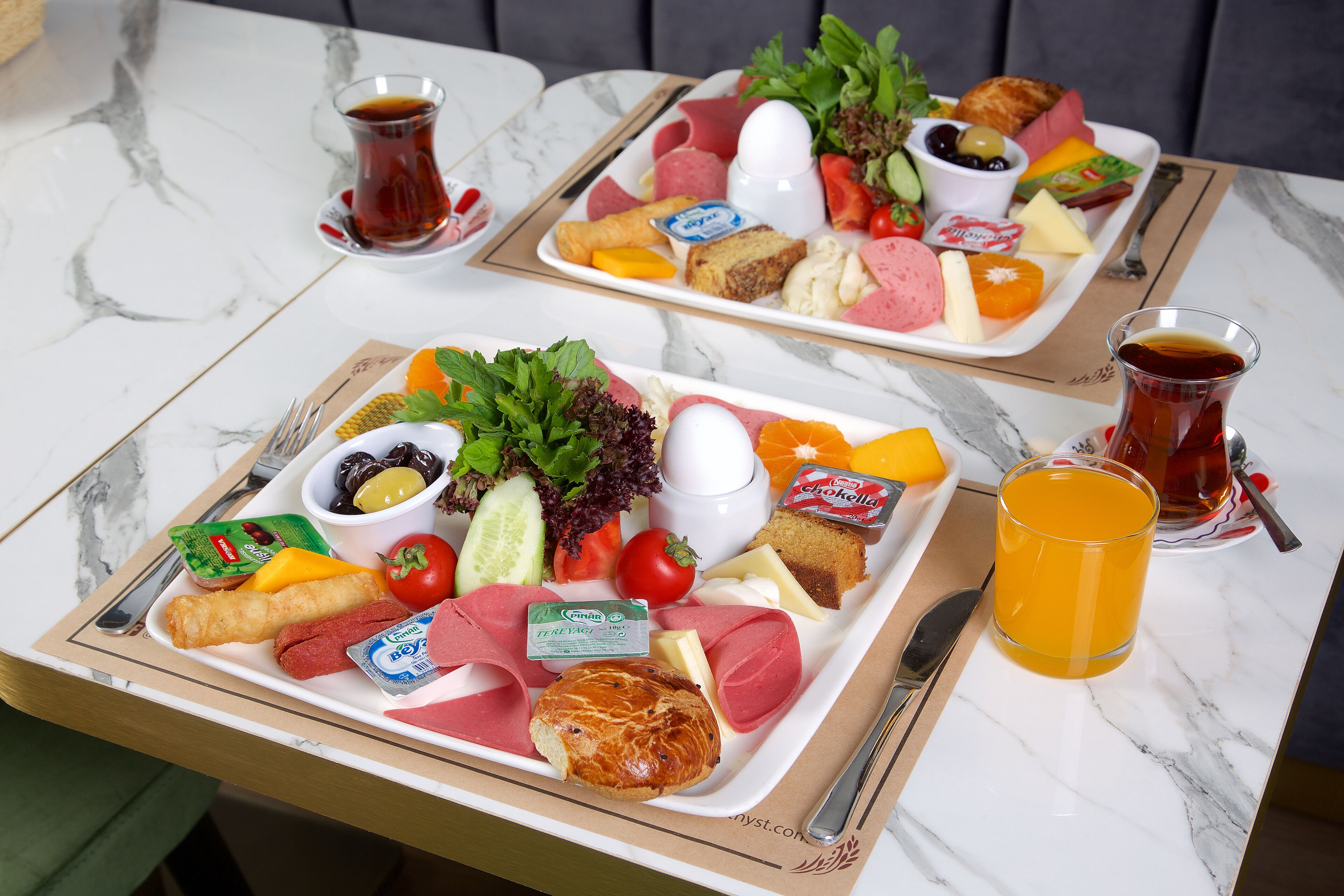 Två brickor med mat och dryck står på ett bord av marmor.