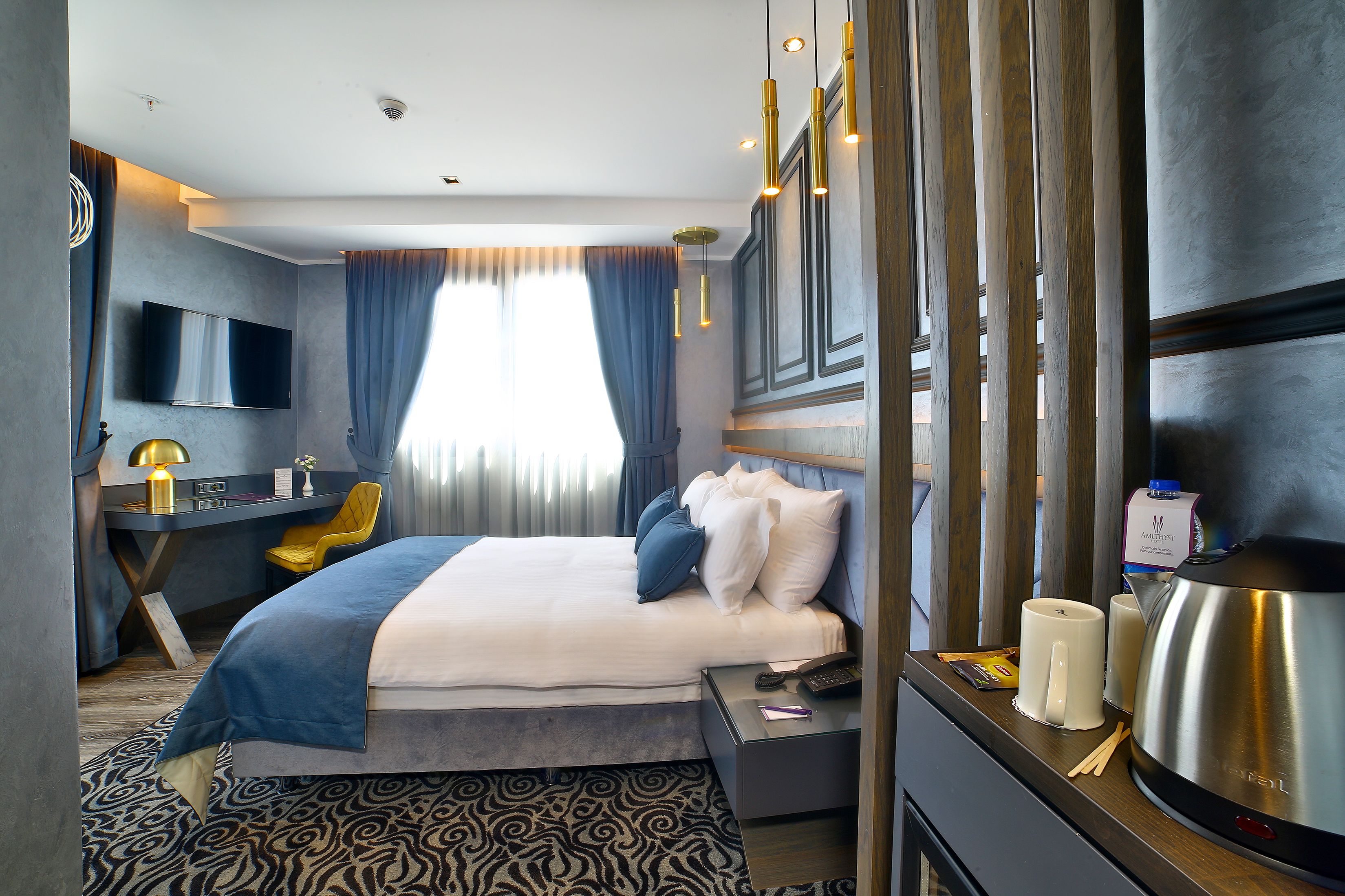 A modern hotel room with a bed, desk, and TV.