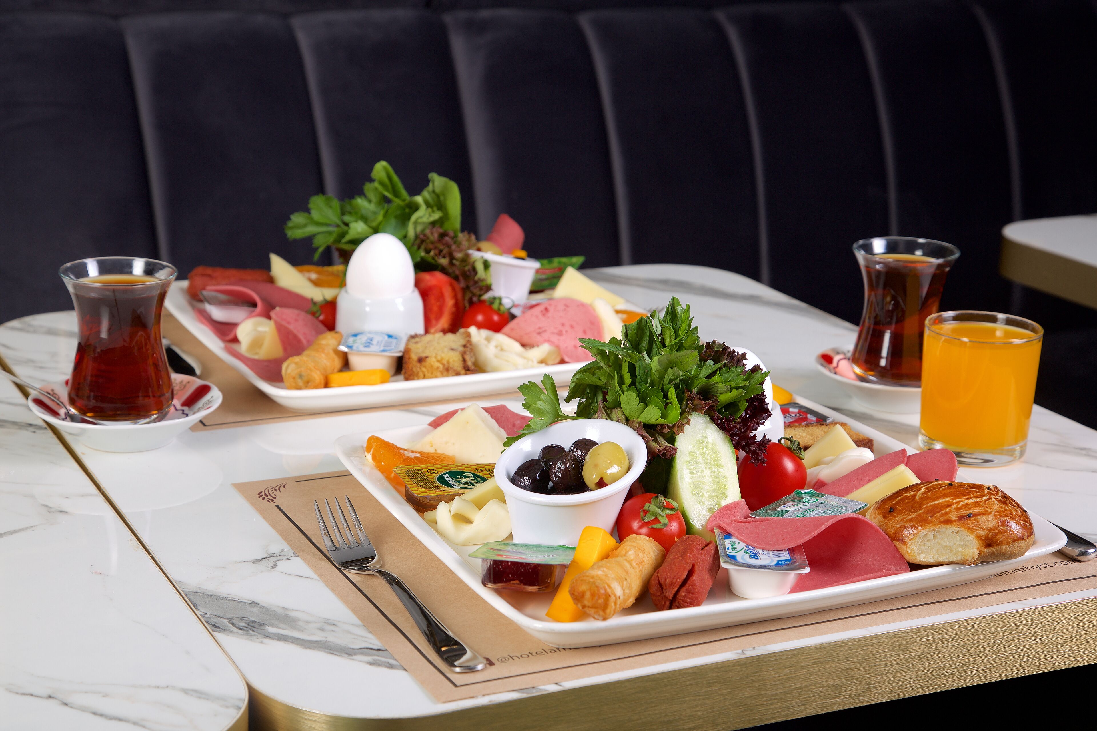 A breakfast tray with various foods and drinks on a marble table.