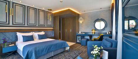 A modern hotel room with a large bed, a seating area, and a vanity with a mirror.