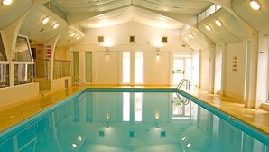 An indoor swimming pool with a high ceiling, clear glass walls, and multiple windows. - St Ives Hotel (Lytham St. Anne's)