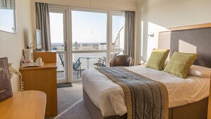 A hotel room with a bed, a desk, a chair, and a balcony with a view. - St Ives Hotel (Lytham St. Anne's)