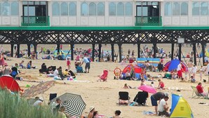 A beach with people relaxing, tents, and a building with a green roof. - St Ives Hotel (Lytham St. Anne's)