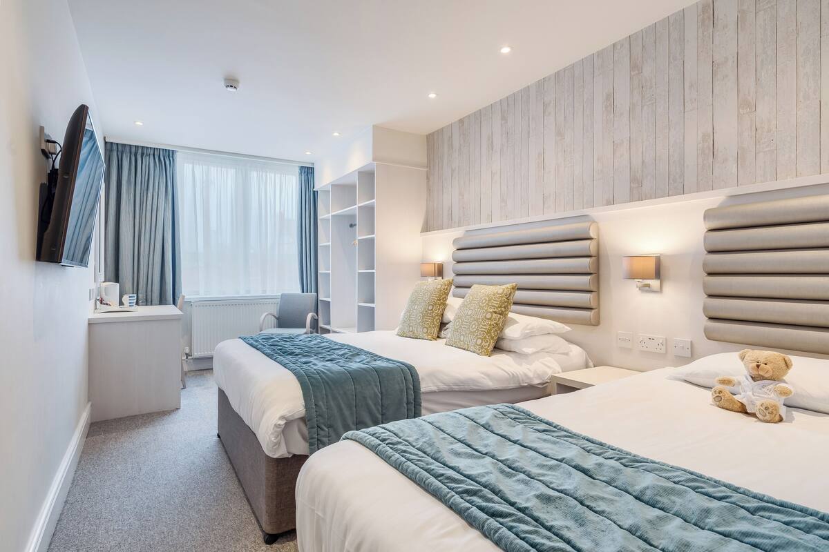 Ett hotellrum med två sängar, ett skrivbord och en TV.