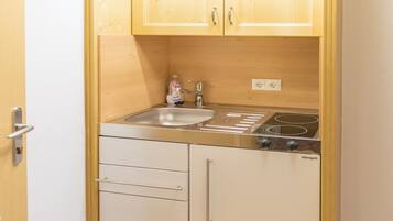 A compact kitchen with wooden cabinets, a built-in stove, and a dishwasher.