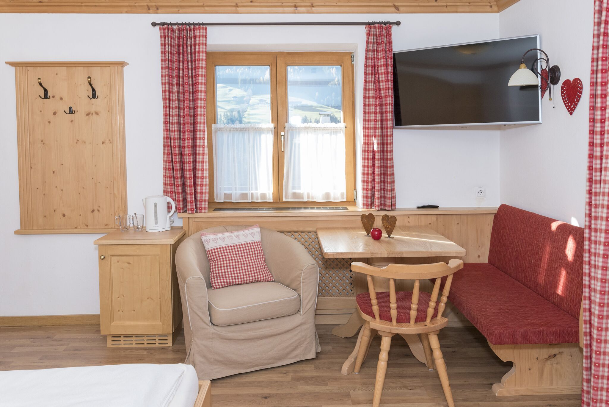 A cozy room with a wooden cabinet, a sofa, a small table with a red apple, and a television on the wall.
