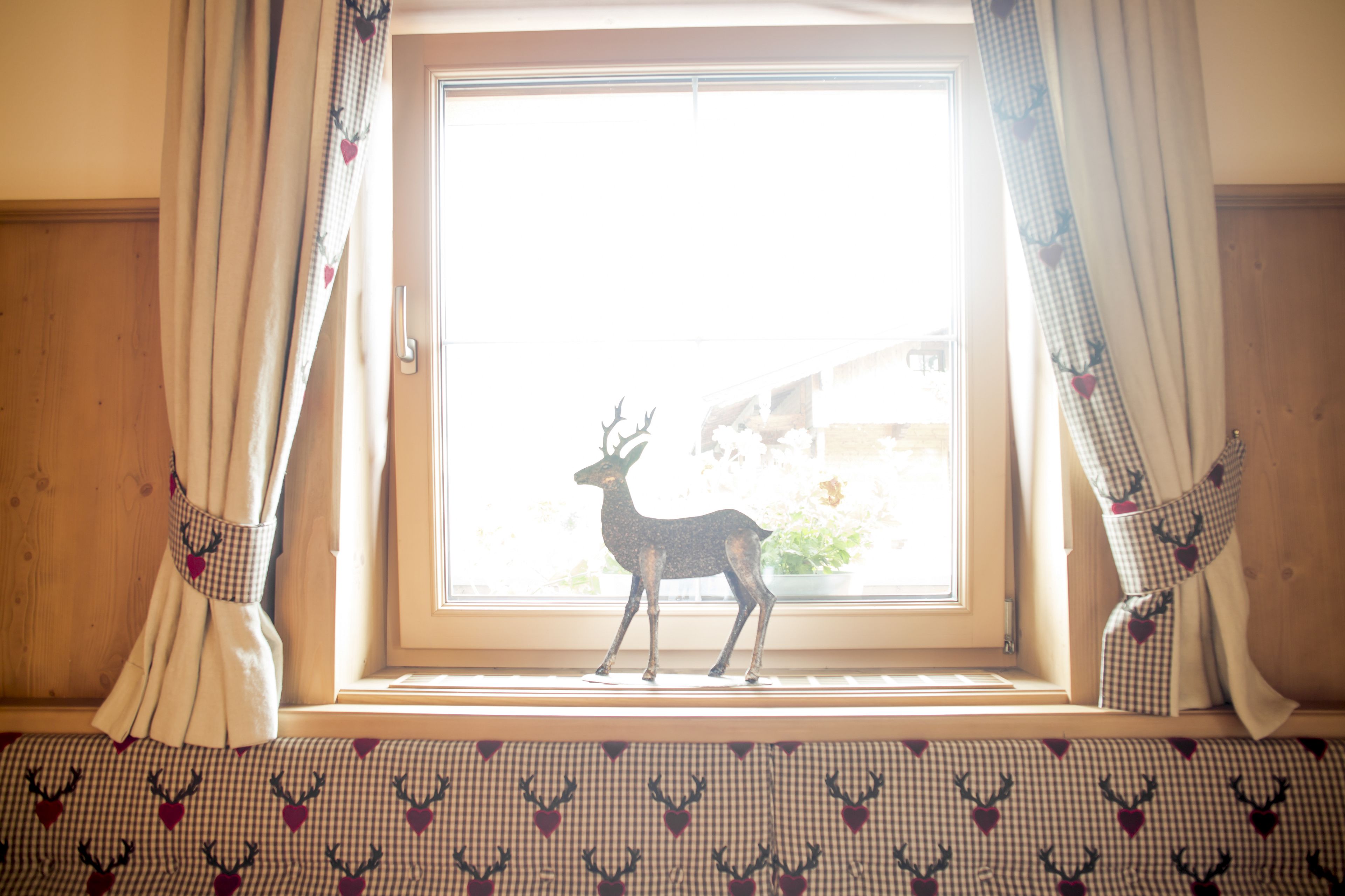 Una ventana con cortinas y una decoración de ciervo.