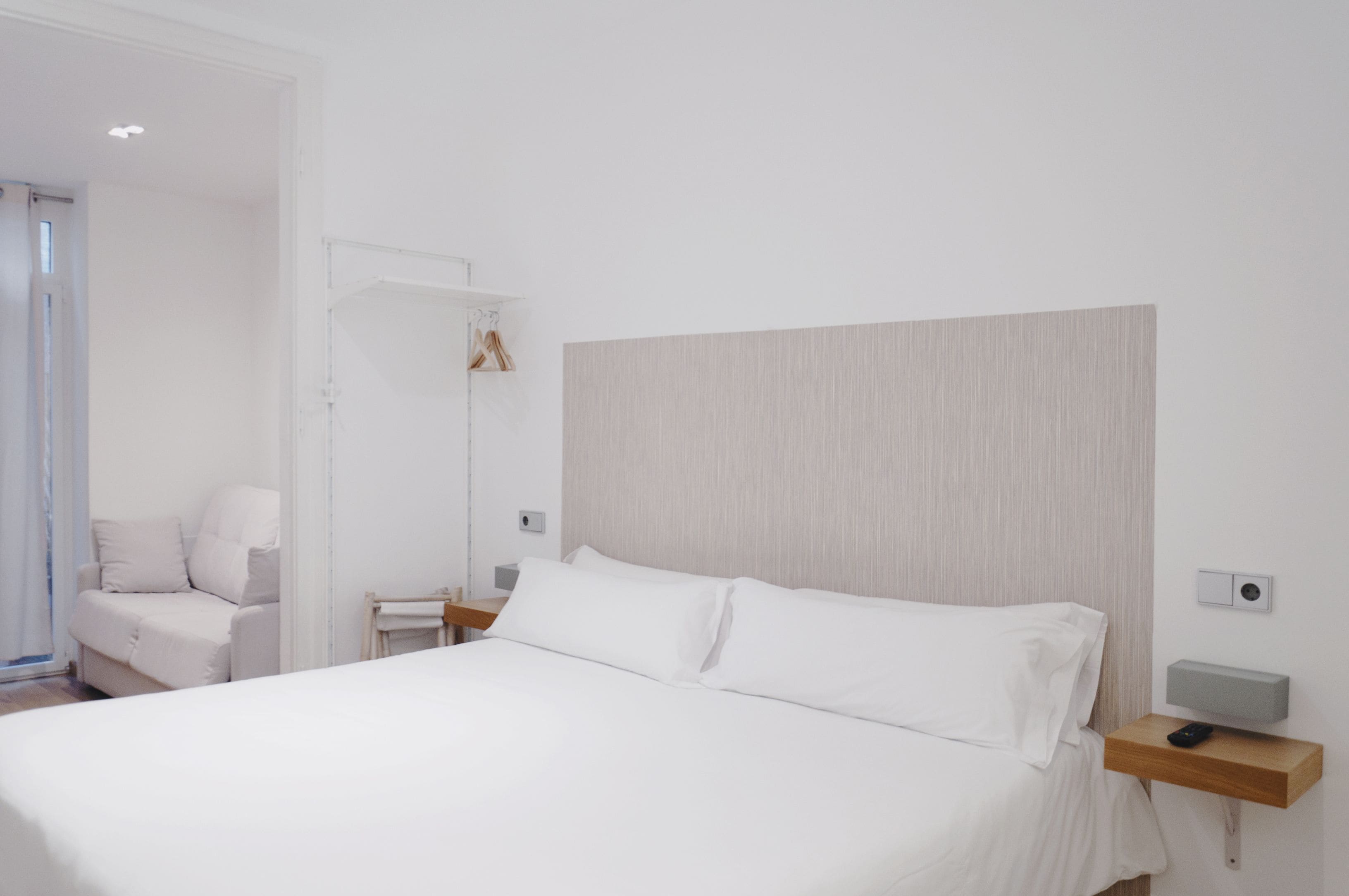 Moderni hotellihuone, jossa on suuri sänky, yöpöytä, yövalaisin ja tuoli.