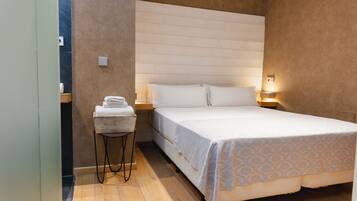 A bedroom with a bed, a nightstand, a small table with towels, and a wall-mounted light.